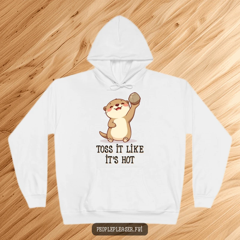 Funny hoodie featuring a delighted otter character gleefully tossing a smooth stone, offering warmth and a dose of playful delight.